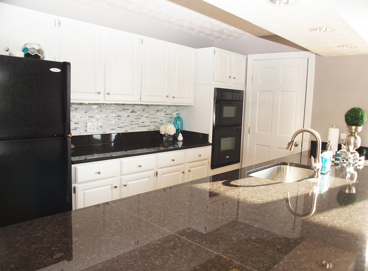 a kitchen with white cabinets and black appliances and granite counter tops