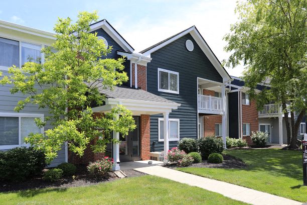 a blue house with a sidewalk and trees in front of it