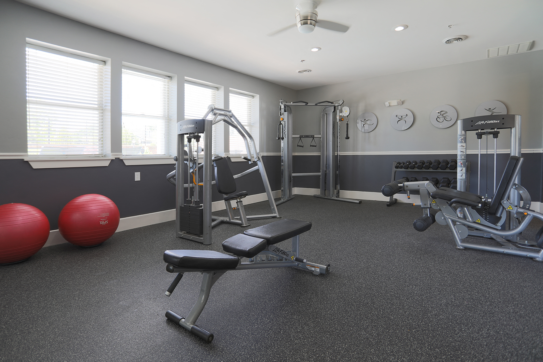 a gym with weights and cardio equipment in a building with windows