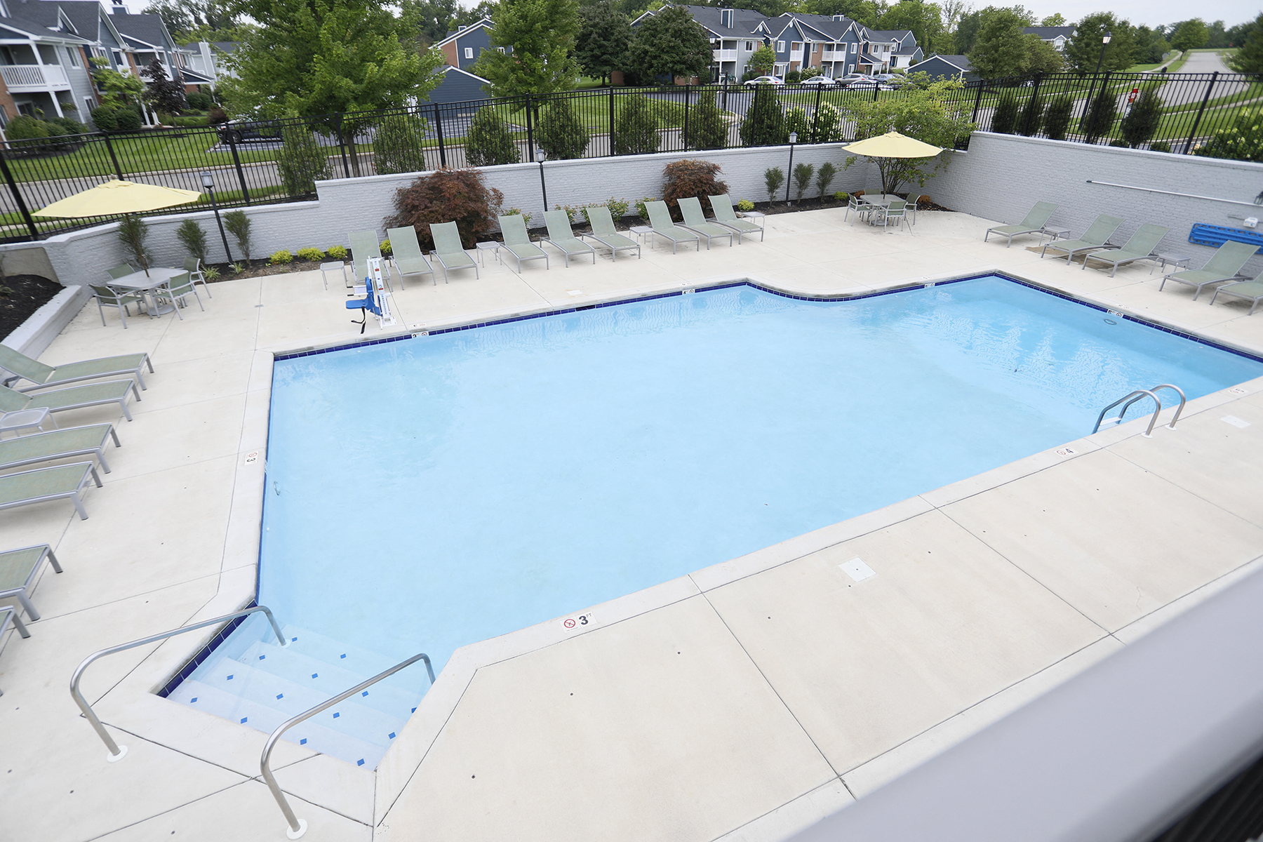 a swimming pool with chairs around it in front of a house