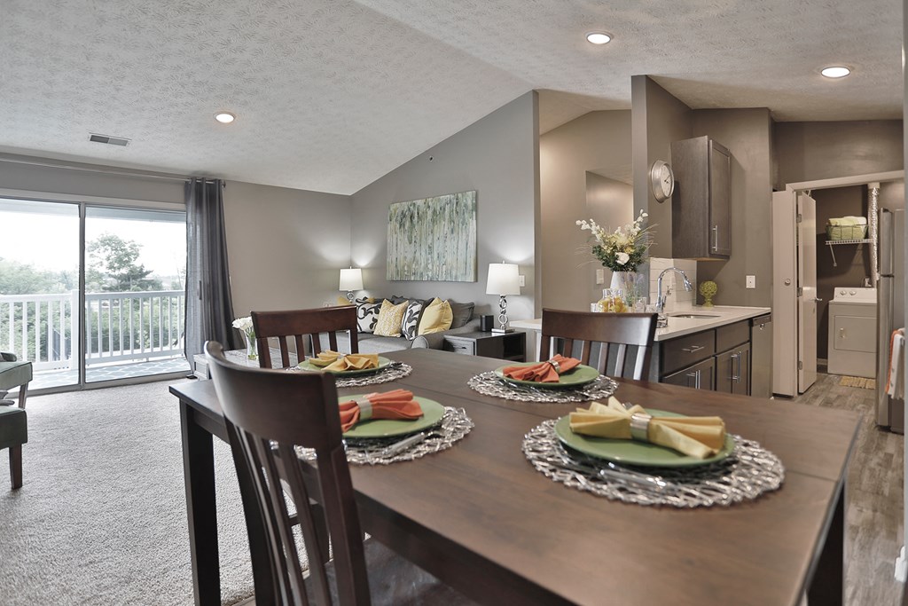 a dining room table with plates of food on it and a kitchen in the background