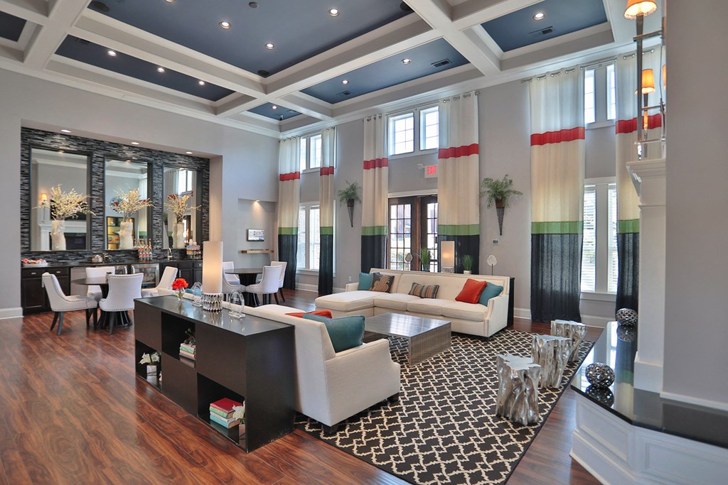 A large, well-lit living room with a wooden floor and a variety of furniture.