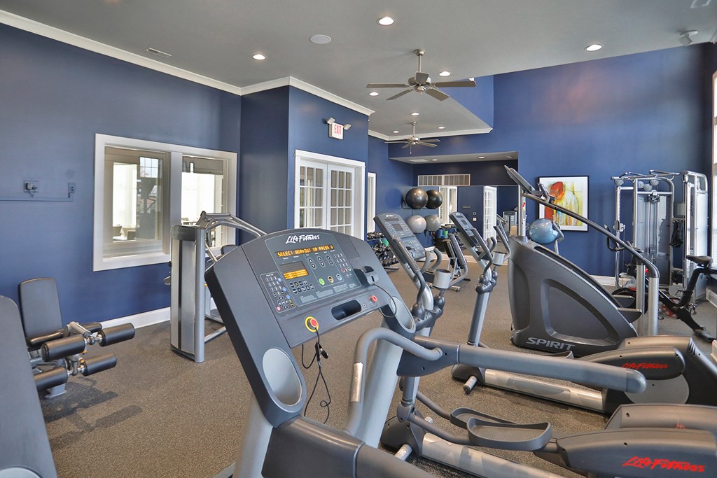 a gym with exercise machines and a ceiling fan