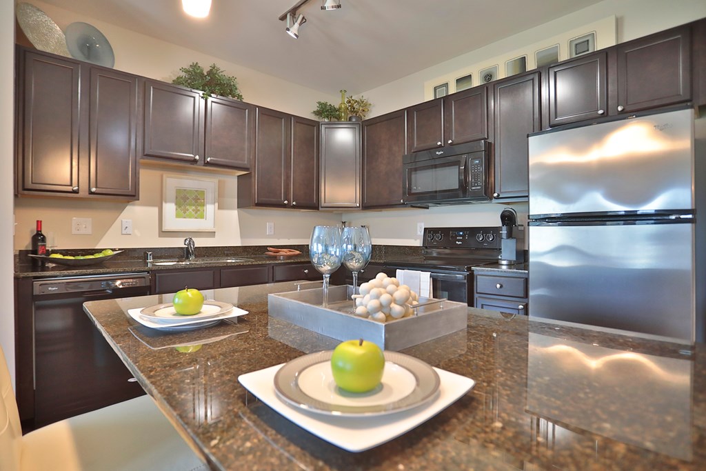 A modern kitchen with a granite countertop and stainless steel appliances.