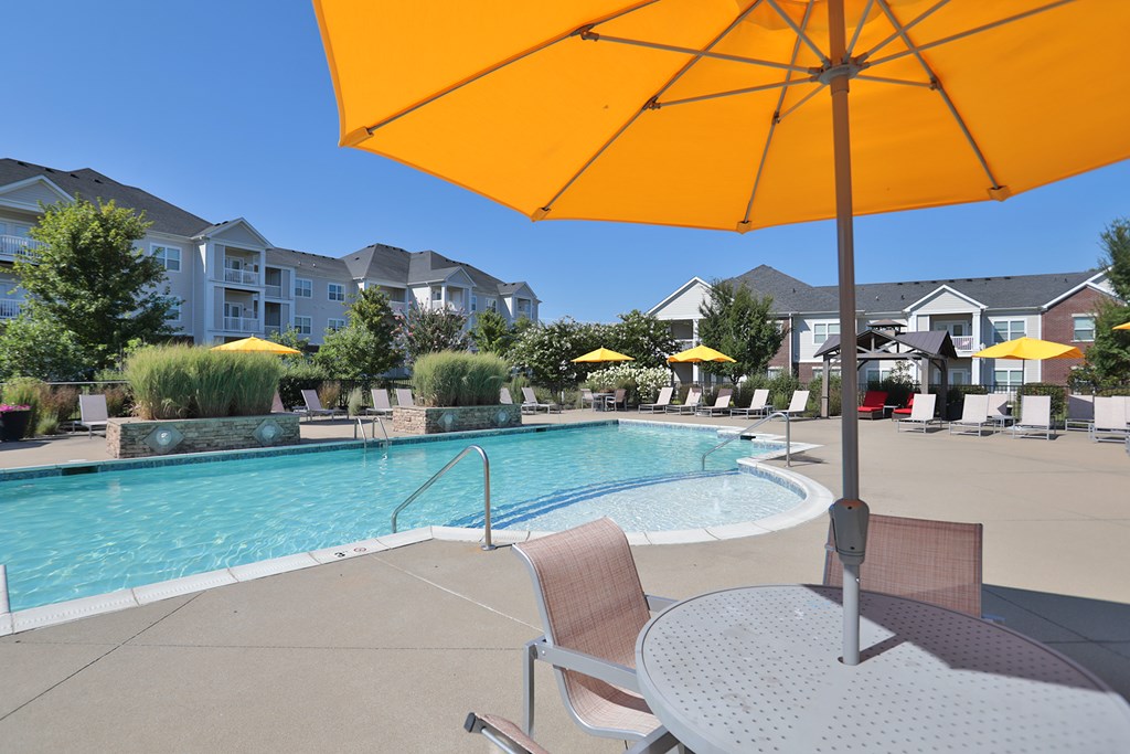 A yellow umbrella is in the foreground of a pool area.