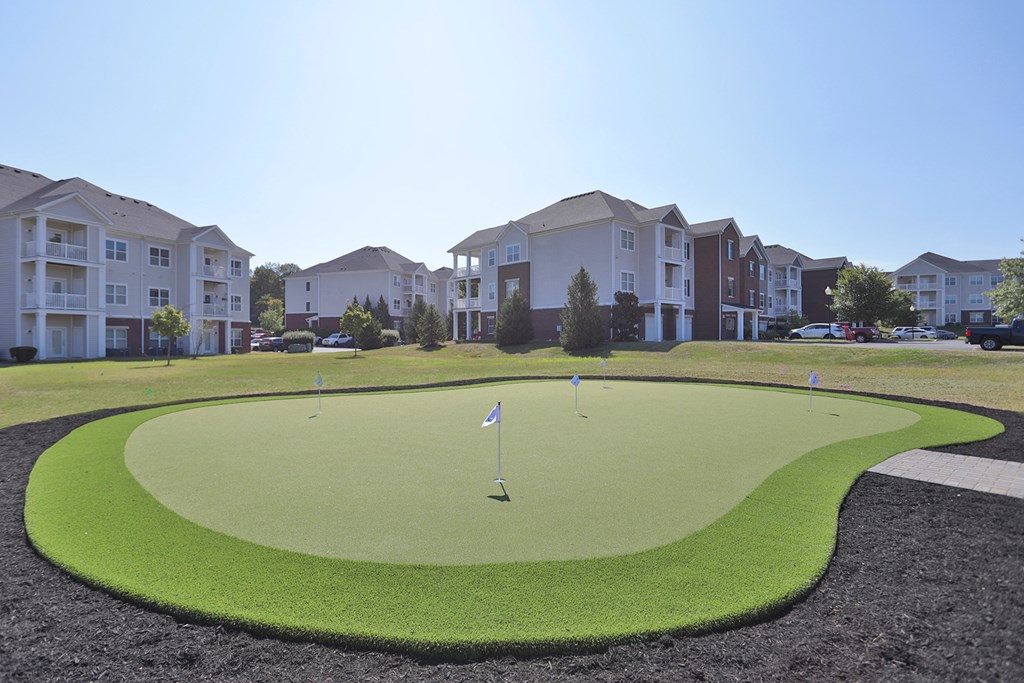 A golf course surrounded by apartment buildings.