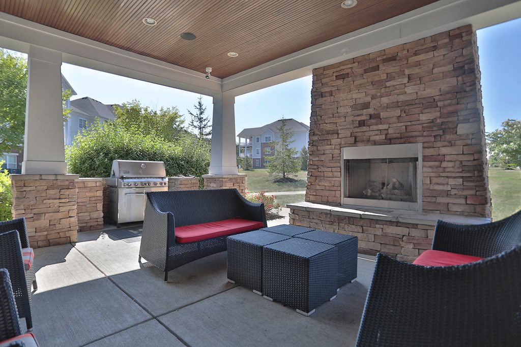A patio with a fireplace and chairs.