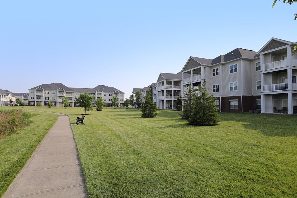 an image of an apartment complex with a green lawn and a bench