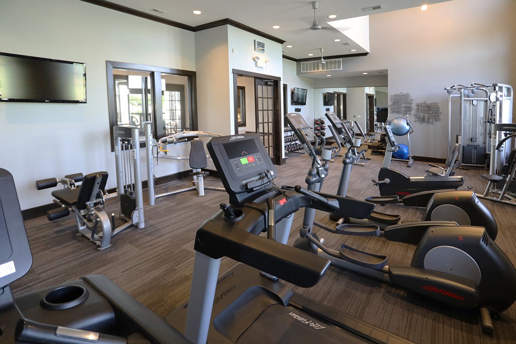 a gym with various exercise machines and a tv