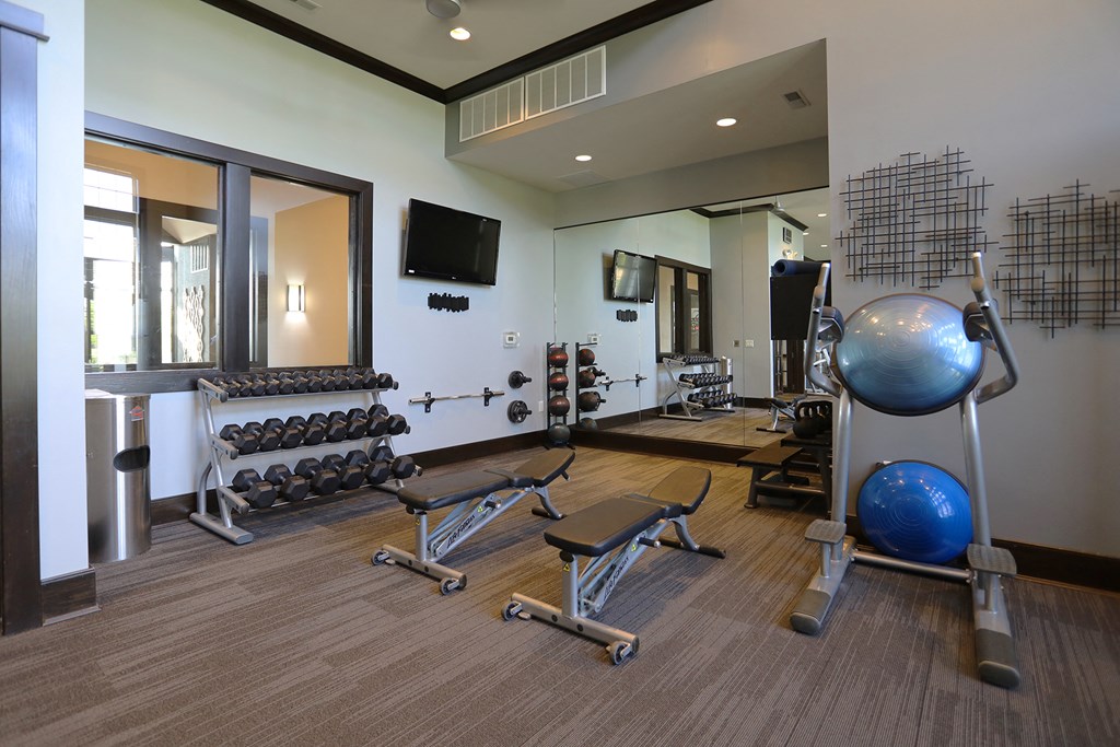 a fitness room with exercise equipment and a television