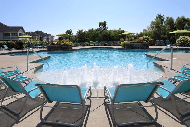a large swimming pool with blue lounge chairs around it