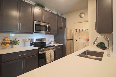 A kitchen with dark brown cabinets and a white countertop.