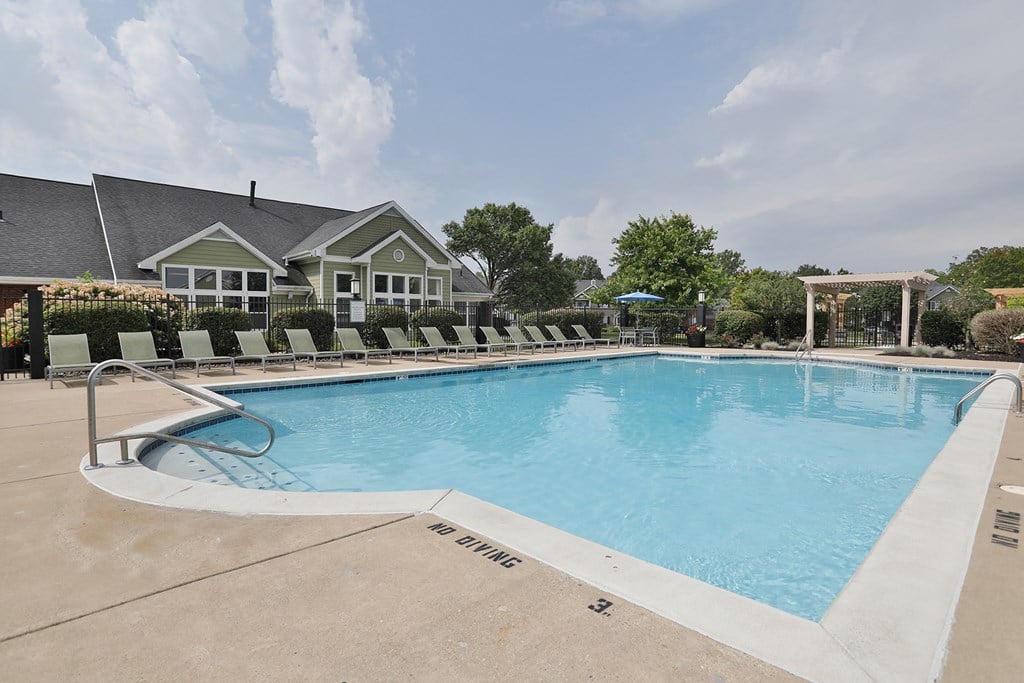 A large outdoor swimming pool with a white fence around it.