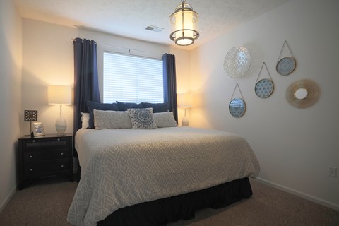 A bedroom with a bed, nightstand, and wall decorations.