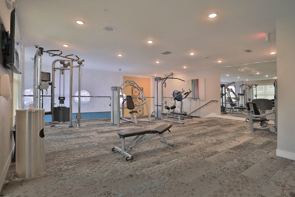 a gym with exercise equipment and a tv on the wall