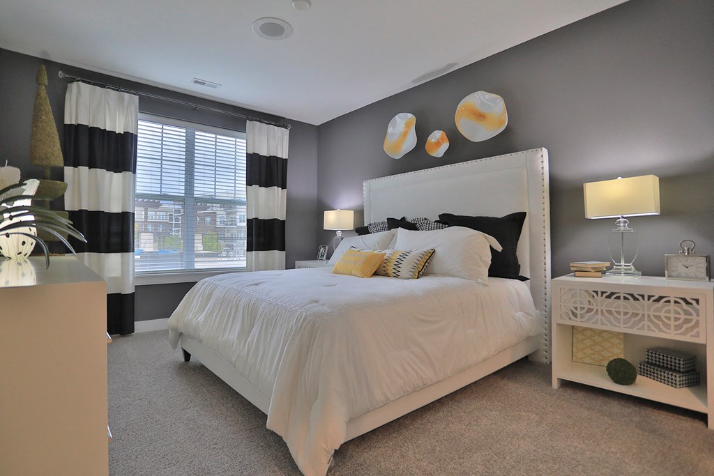 a bedroom with a white bed and black and white curtains