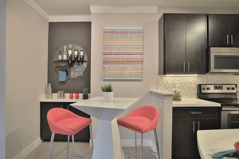 a kitchen with a white table and pink chairs