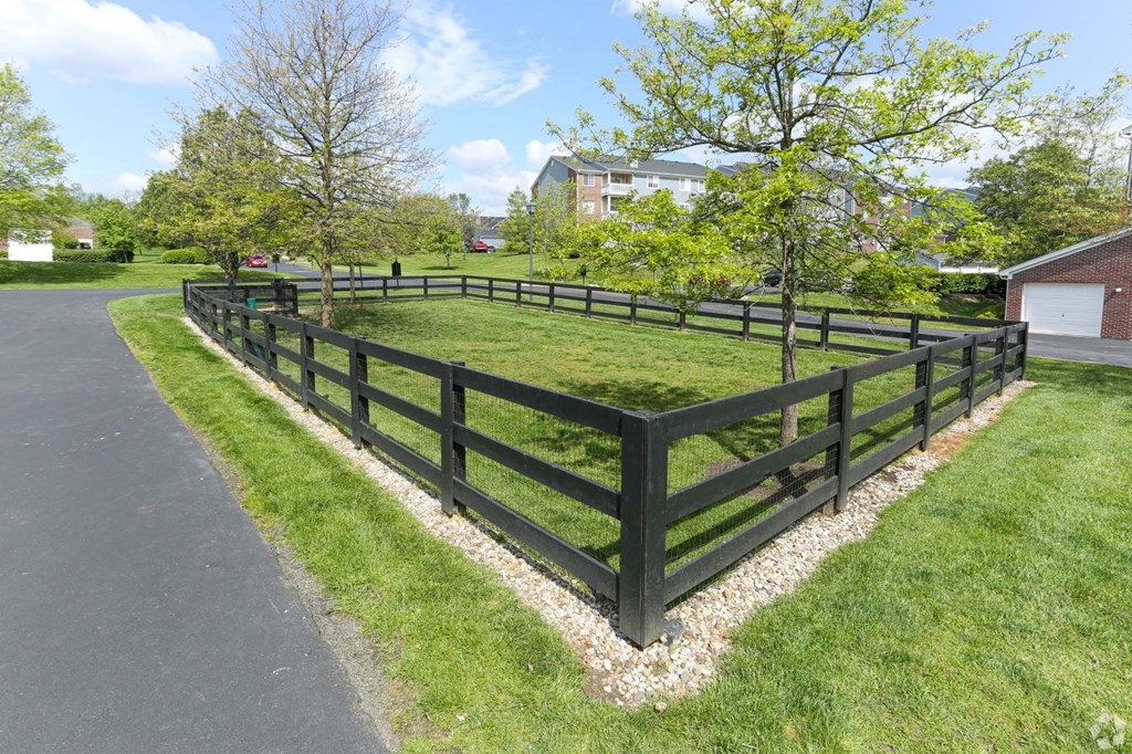 a wooden fence around a grassy area next to a street
