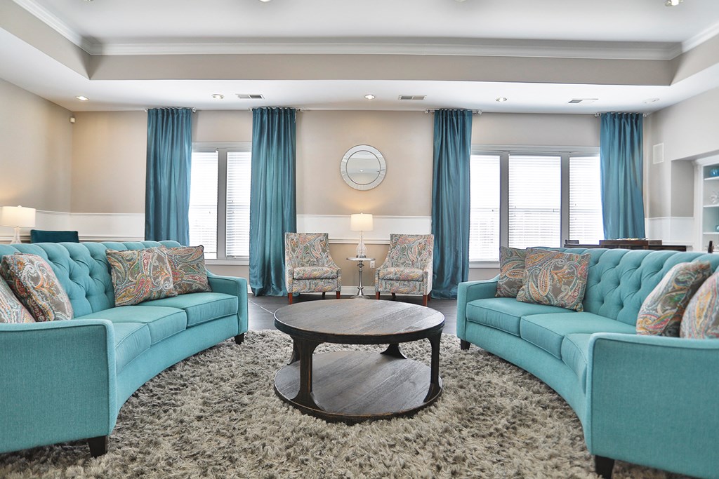 a living room with blue couches and chairs and a table