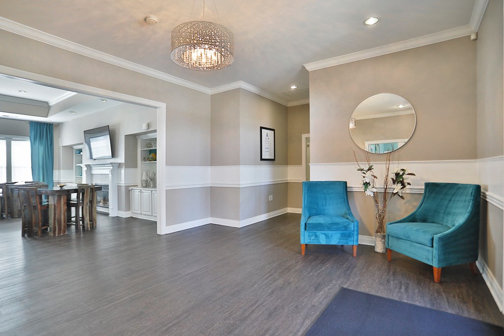 a living room with blue chairs and a mirror