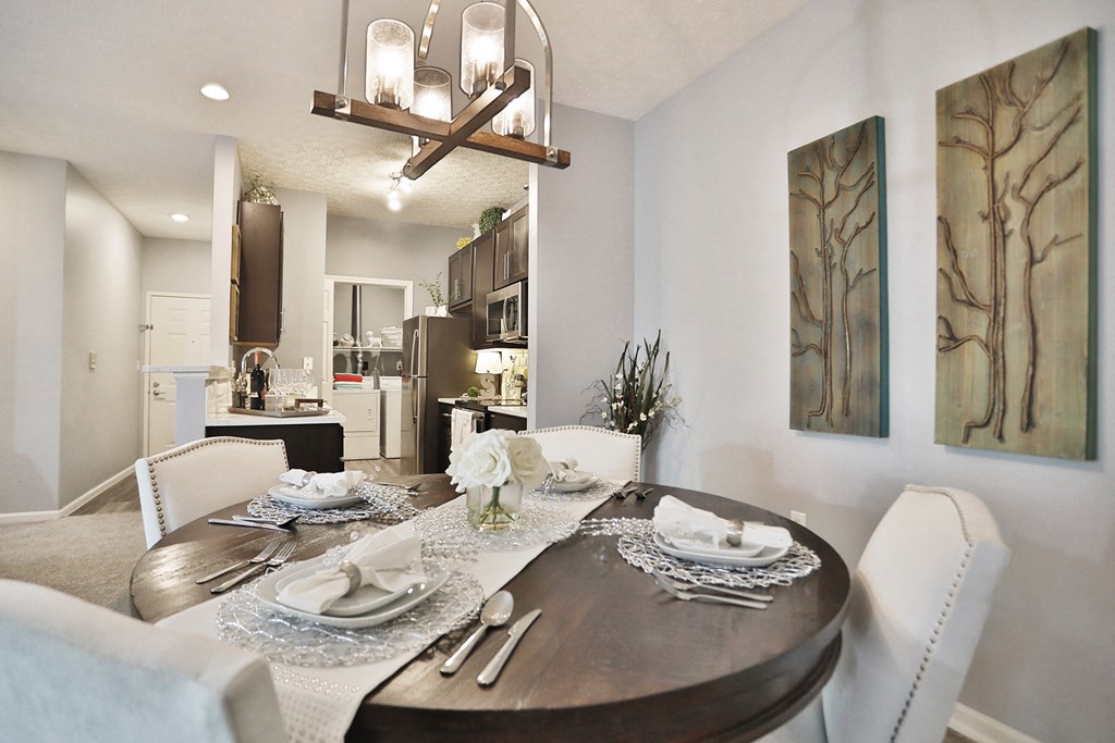 a dining room table with white chairs and a chandelier