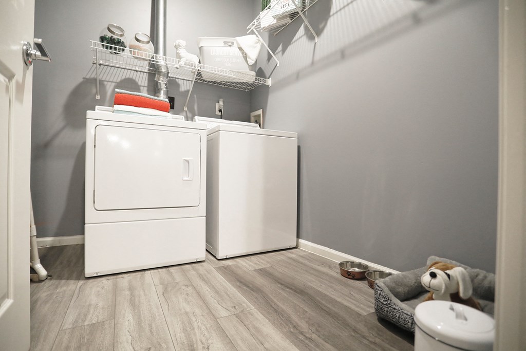 a white washer and dryer in a laundry room with grey walls and wood