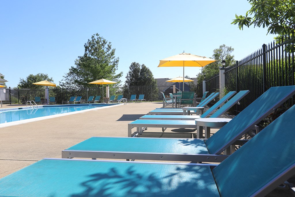 a pool with blue lounge chairs and yellow umbrellas