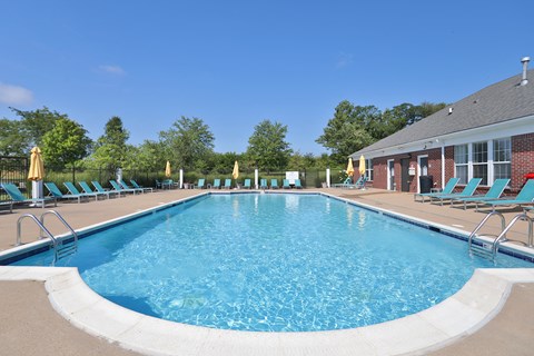 A large outdoor swimming pool with blue water and lounge chairs around it.