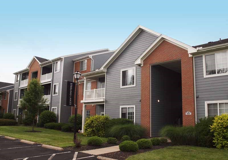 an apartment building with a sidewalk and grass