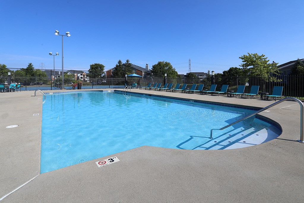 a pool with blue chairs around it and a blue sky