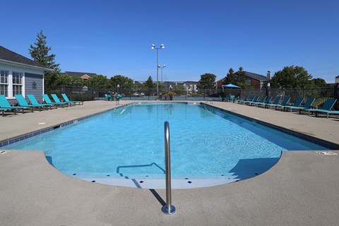 an empty pool with blue chairs around it