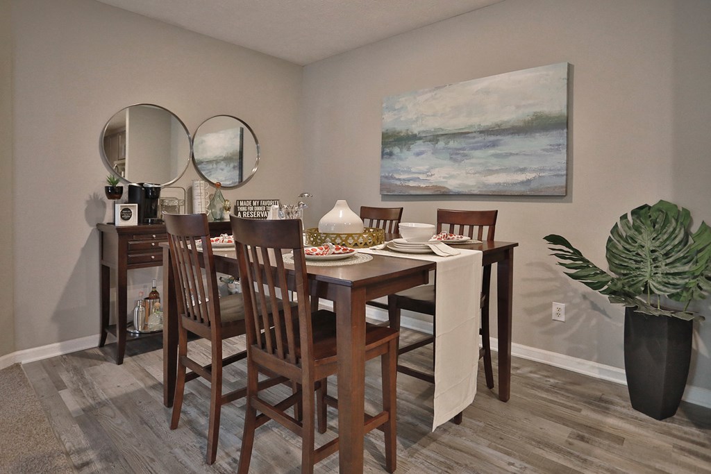 a dining room with a table and chairs and a painting on the wall