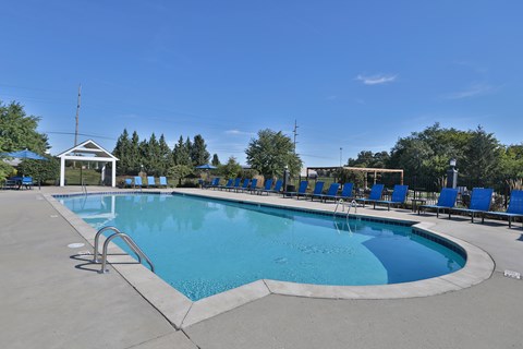 A large outdoor swimming pool with a diving board and lounge chairs.