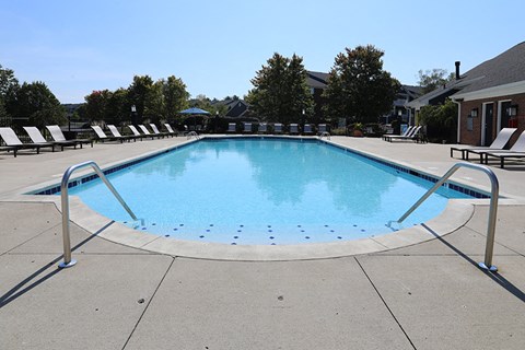 a swimming pool with chairs around it in front of a house