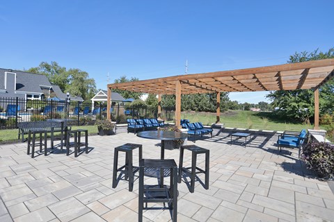 A patio with a table and chairs under a wooden pergola.