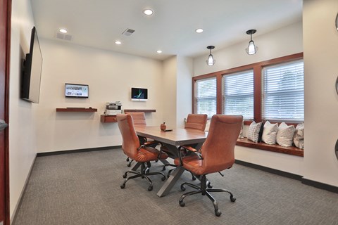 A conference room with a table, chairs, and a TV mounted on the wall.