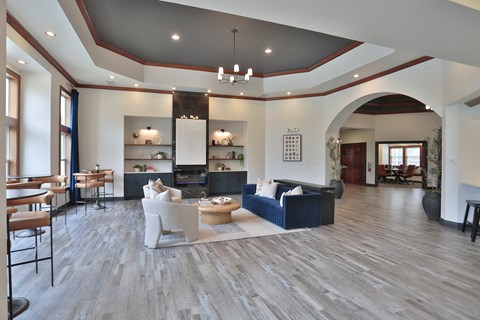 A spacious living room with a dark blue sofa and wooden flooring.