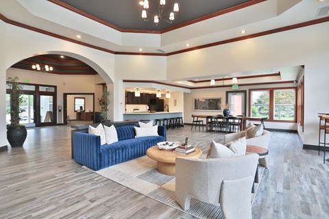 A large, modern living room with a blue sofa and wooden floors.