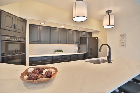 A modern kitchen with dark grey cabinets and a marble countertop.