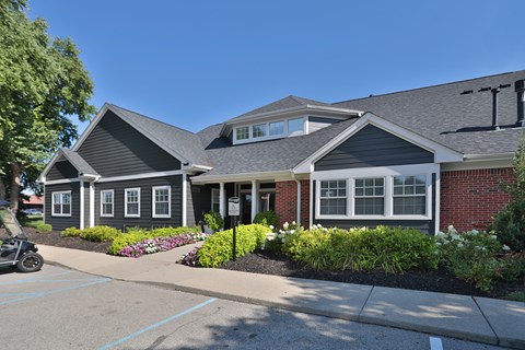 A building with a grey roof and a parking lot in front.