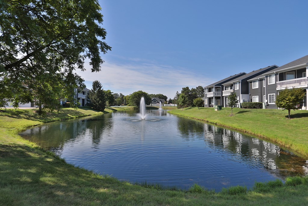 a pond with two fountains in the middle of an apartment complex