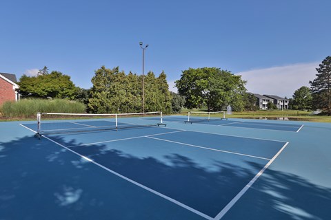 A tennis court with a net and white lines on a blue surface.