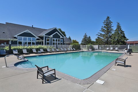 A large swimming pool with lounge chairs and a building in the background.