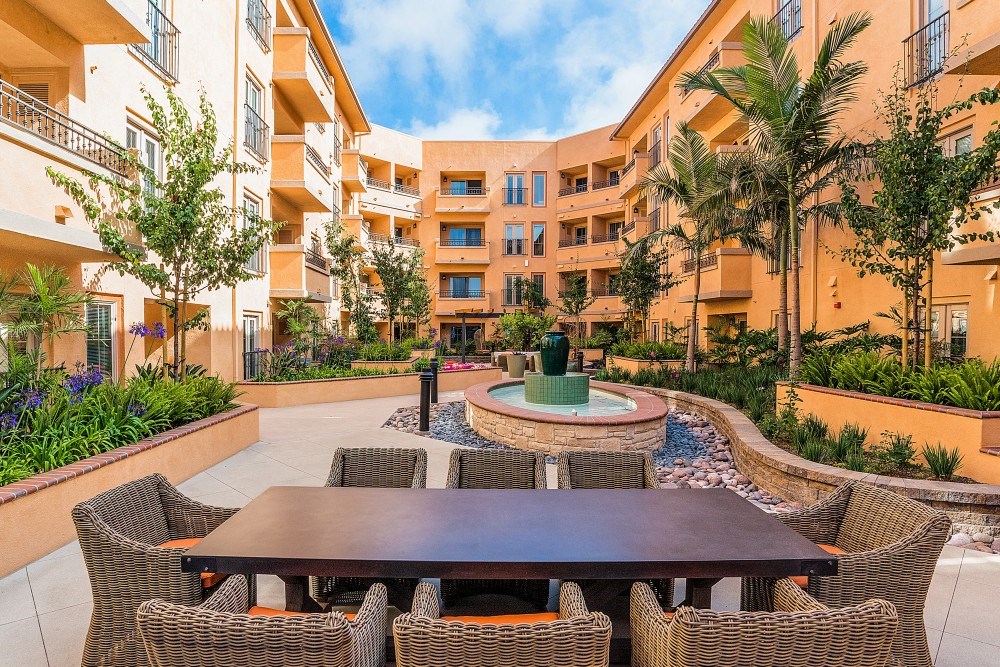 a courtyard with a table and chairs in front of an apartment building