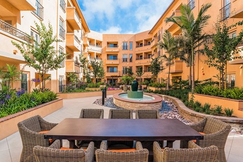 a courtyard with a table and chairs in front of an apartment building
