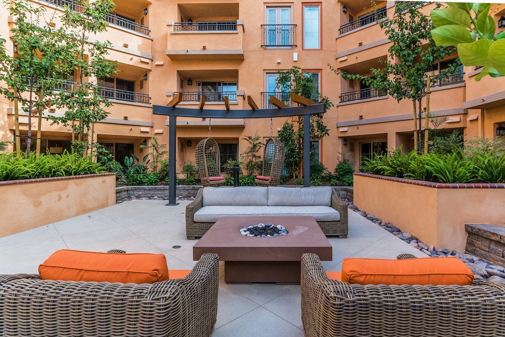 a patio with a couch and a coffee table in front of an apartment building