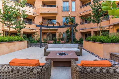a patio with a couch and a coffee table in front of an apartment building