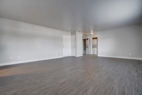 an empty living room with wood floors and white walls