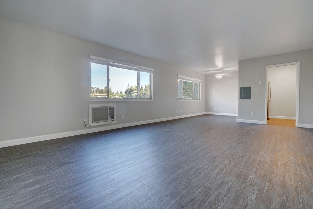 an empty living room with wood floors and a window