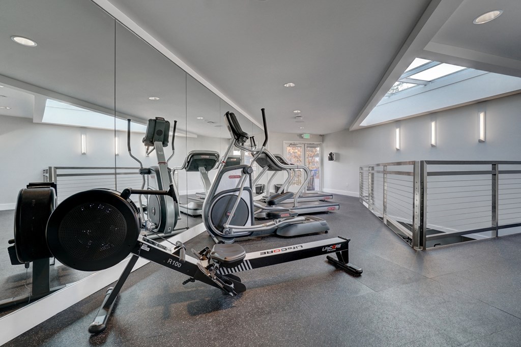 a gym with cardio equipment on the floor and mirrored walls